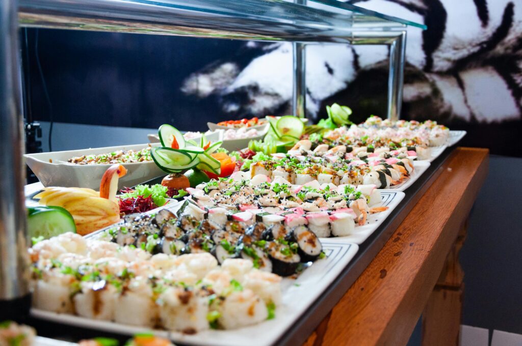 A colorful and diverse sushi buffet featuring an array of fresh rolls, garnished with vegetables.