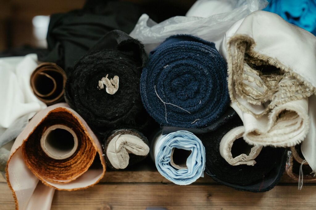 A close-up of various fabric rolls in a workshop, showcasing textures and colors.